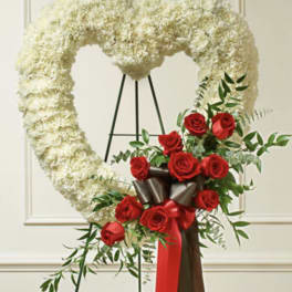 Heart-shaped white floral wreath with red roses and ribbon