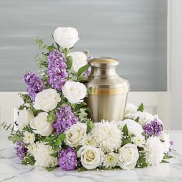 White and purple floral arrangement around a metal urn
