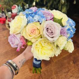Handheld bouquet of pastel roses and blue hydrangeas