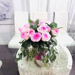 Pink roses arranged in a vase with trailing greenery