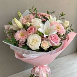 Pink and white bouquet with roses, lilies, and daisies wrapped in pastel paper