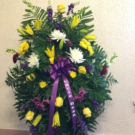 Standing funeral spray with yellow and white flowers and a purple ribbon