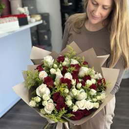 Woman holding a large bouquet of red and white roses wrapped in brown paper.