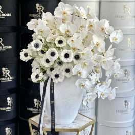 White orchids and anemones arranged in a white vase