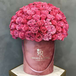 Large pink rose arrangement in a round velvet hatbox