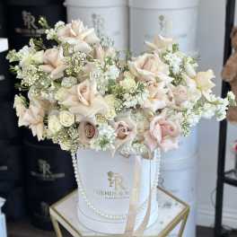 Blush and white rose arrangement in a white hatbox with ribbon