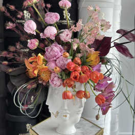 Colorful floral arrangement in a white face-shaped vase