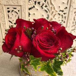 Red roses in a decorative round container with ivy accents