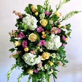 Tall floral spray with white hydrangeas, yellow roses, and pink daisies