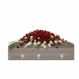 Red and white floral casket spray on a gray casket