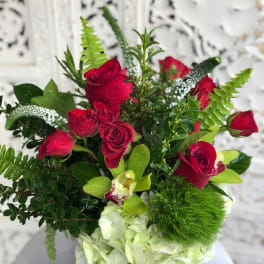 Red roses and white hydrangea in a vase with green accents