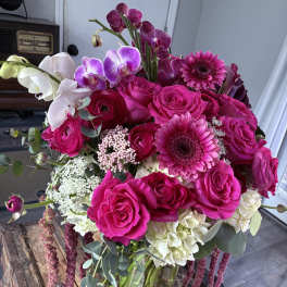 Bouquet of hot pink roses, orchids, and gerbera daisies in a glass vase