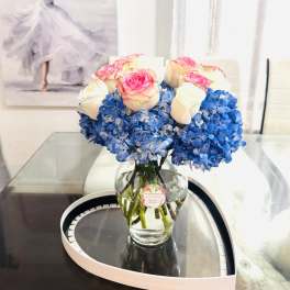 Blue hydrangeas and pink-white roses arranged in a glass vase
