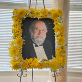 Framed portrait surrounded by a yellow chrysanthemum floral wreath