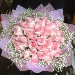 Bouquet of pale pink roses with white baby's breath in lavender wrapping