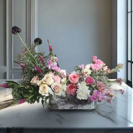 Low floral arrangement with pink and cream roses in a rectangular vase