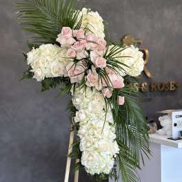 Large cross-shaped floral arrangement of white and pink roses