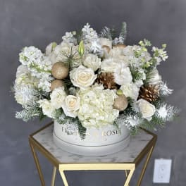 White floral arrangement with roses and hydrangeas in a round box