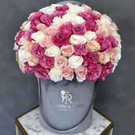 Round bouquet of pink and white roses in a gray hatbox