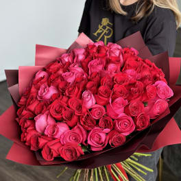 Large bouquet of pink and red roses wrapped in burgundy paper