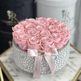 Pink roses arranged in a round silver box with a pink ribbon