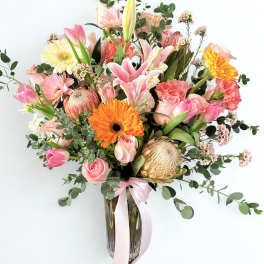 Pink and peach mixed bouquet in a glass vase with a ribbon