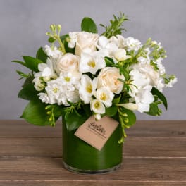 White and cream floral arrangement in a green glass vase