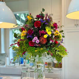 Tall mixed bouquet in a clear glass vase on a kitchen island
