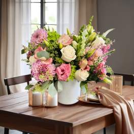 Pink and white flower arrangement in a white vase on a table