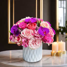 Pink and purple rose bouquet in a white vase beside candles