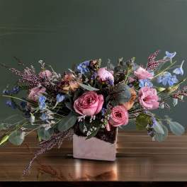 Pink roses and blue flowers in a square vase