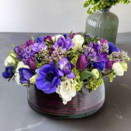 Purple and white flower arrangement in a low glass vase