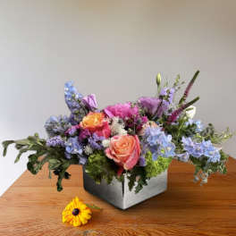 Mixed bouquet in a square metal container with pink, purple, and blue flowers