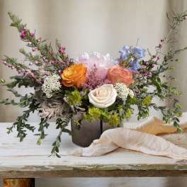 Mixed bouquet of roses and pastel blooms in a dark vase