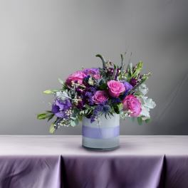 Pink and purple flower arrangement in a striped glass vase