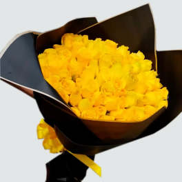Bouquet of yellow roses wrapped in dark paper with a yellow ribbon