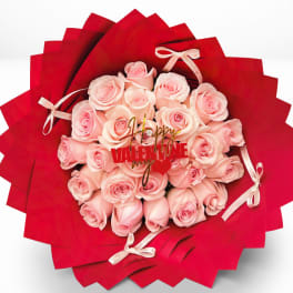 Pink roses arranged in red wrapping with small ribbon bows