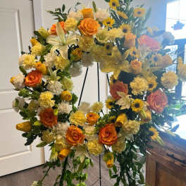 Large floral wreath with orange roses, yellow lilies, and sunflowers