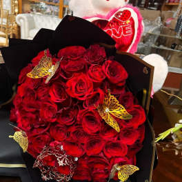 Bouquet of red roses wrapped in black paper with gold butterfly accents