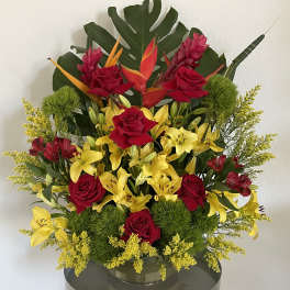 Tall arrangement of red roses and yellow lilies with tropical foliage