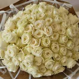 Large bouquet of cream-white roses wrapped in brown paper with white ribbon