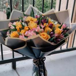 Bouquet of yellow roses and pink flowers in a glass vase