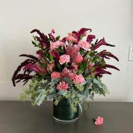 Pink and burgundy floral arrangement in a glass vase