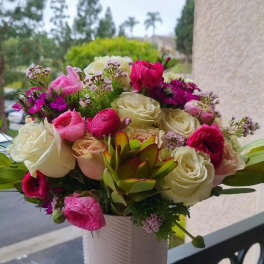 Pink and white rose bouquet in a white vase with a succulent accent