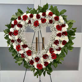 Heart-shaped wreath of red and white flowers on a stand