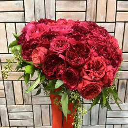 Red rose bouquet with greenery in a red vase
