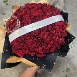 Large bouquet of red roses wrapped in black and gold paper with a white ribbon