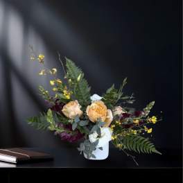Peach and white roses in a white vase with yellow accent flowers