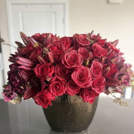 Red roses and dark lilies arranged in a dark vase