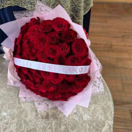 Large bouquet of red roses wrapped in pink paper with a ribbon